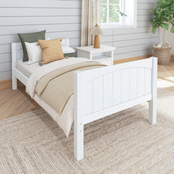 White wooden bed frame with cozy pillows and comforter in a modern bedroom with natural lighting.