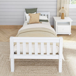 White wooden twin bed with beige bedding and pillows, next to a nightstand and lamp in a cozy, modern bedroom.