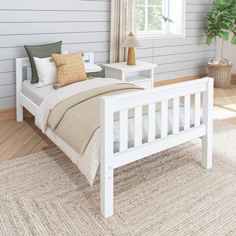 Cozy modern farmhouse bedroom with white wooden bed, neutral layered bedding, textured throw pillows, wooden table lamp, shiplap wall, woven jute rug and wicker-basket fiddle leaf fig