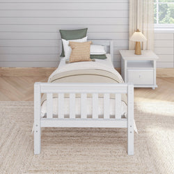 Toddler bed with white frame, cozy bedding, and decorative pillows in a bright, modern bedroom setting.