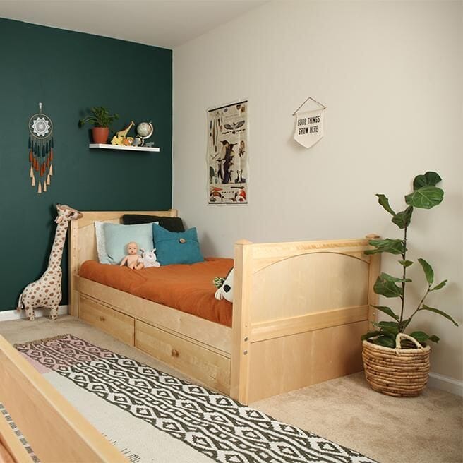 Modern kids bedroom with green accent wall, wooden bed, and playful decor elements.