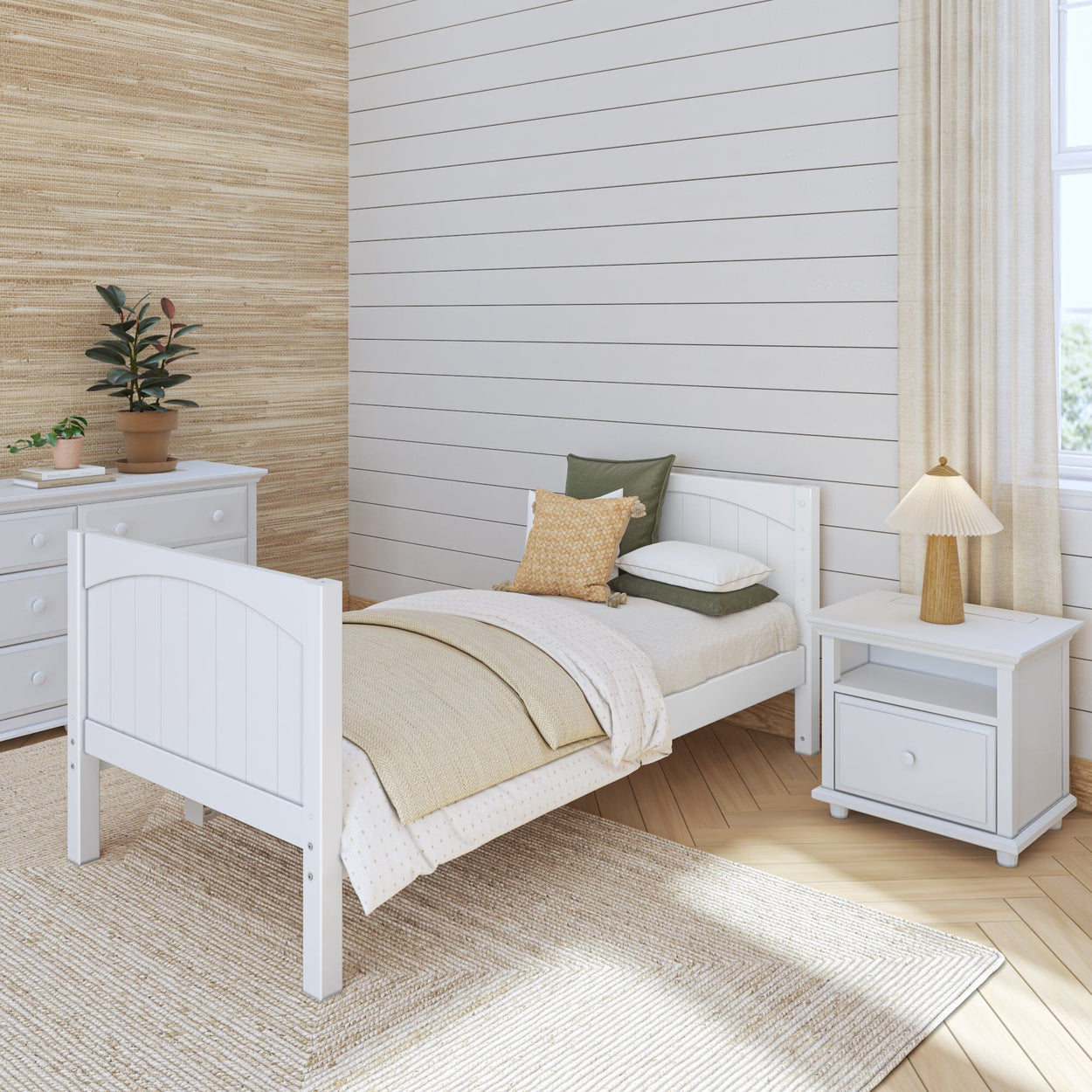 Minimalist bedroom with white twin bed, nightstand, dresser, and modern decor including plants and a woven rug.