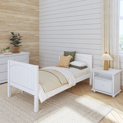 Minimalist bedroom with white twin bed, nightstand, dresser, and modern decor including plants and a woven rug.