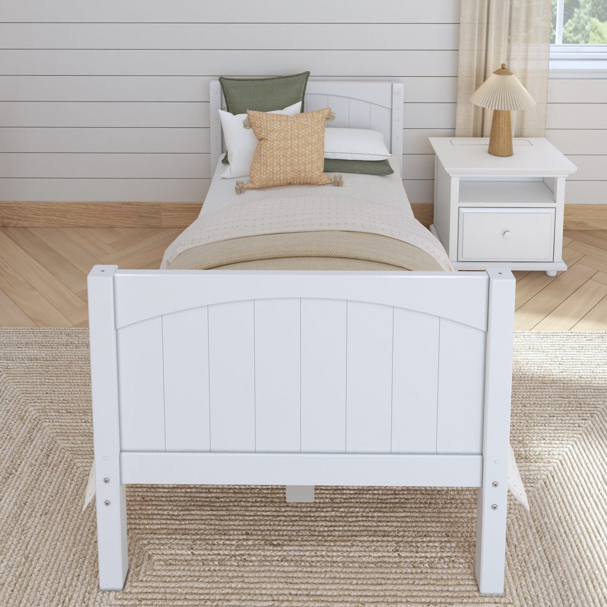 Single white wooden bed with neutral bedding and pillows, placed on a woven rug in a cozy bedroom setting.