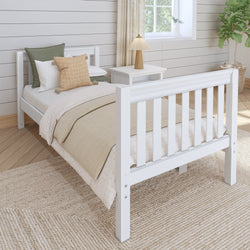 Cozy bedroom with a white wooden bed frame, neutral bedding, decorative pillows, and a side table lamp.