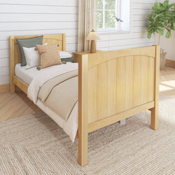 Wooden bed frame in cozy bedroom with neutral bedding and decorative pillows, next to a lamp and large plant, perfect for a serene space.