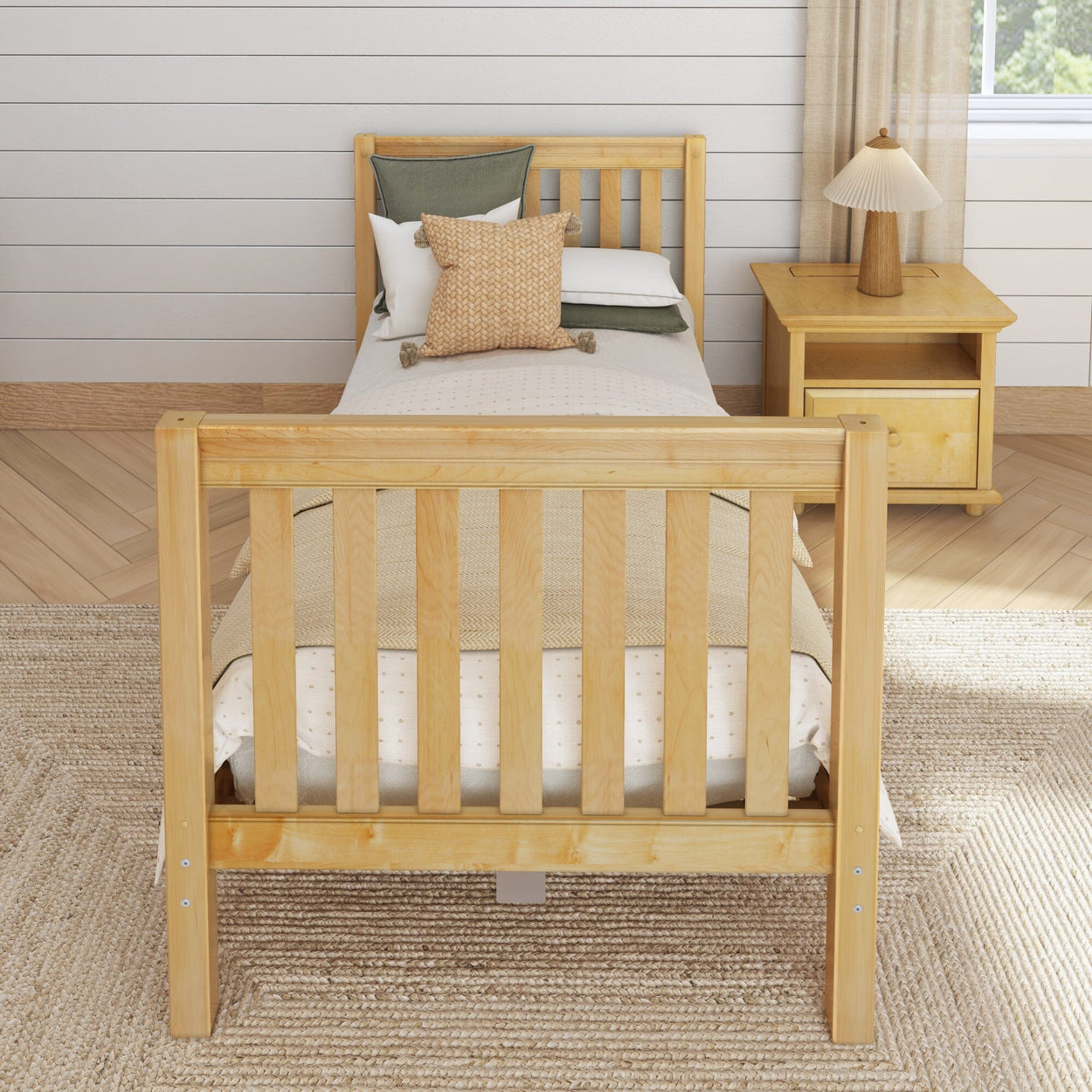 Wooden single bed with beige bedding and pillows in a modern bedroom with a nightstand and lamp, hardwood floor, and neutral decor.