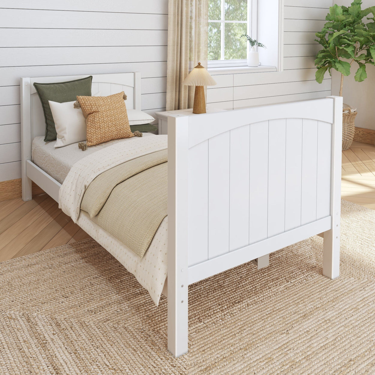 White wooden bed frame in cozy bedroom with green and beige accent pillows and potted plant for modern interior design.