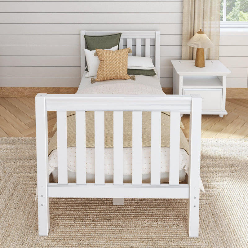 Minimalist bedroom with white wooden single bed, neutral bedding and woven throw pillows, white nightstand with wooden table lamp, shiplap wall and natural jute rug