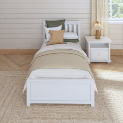 Single white wooden bed with beige linens and a nightstand in a cozy, modern bedroom setting.