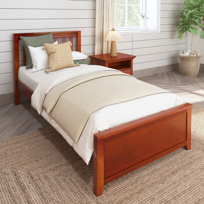 Cozy farmhouse bedroom with wooden single bed, beige layered bedding and knit accent pillows, cherry wood nightstand with pleated lamp, white shiplap wall, woven jute rug and potted plant by a sunlit window