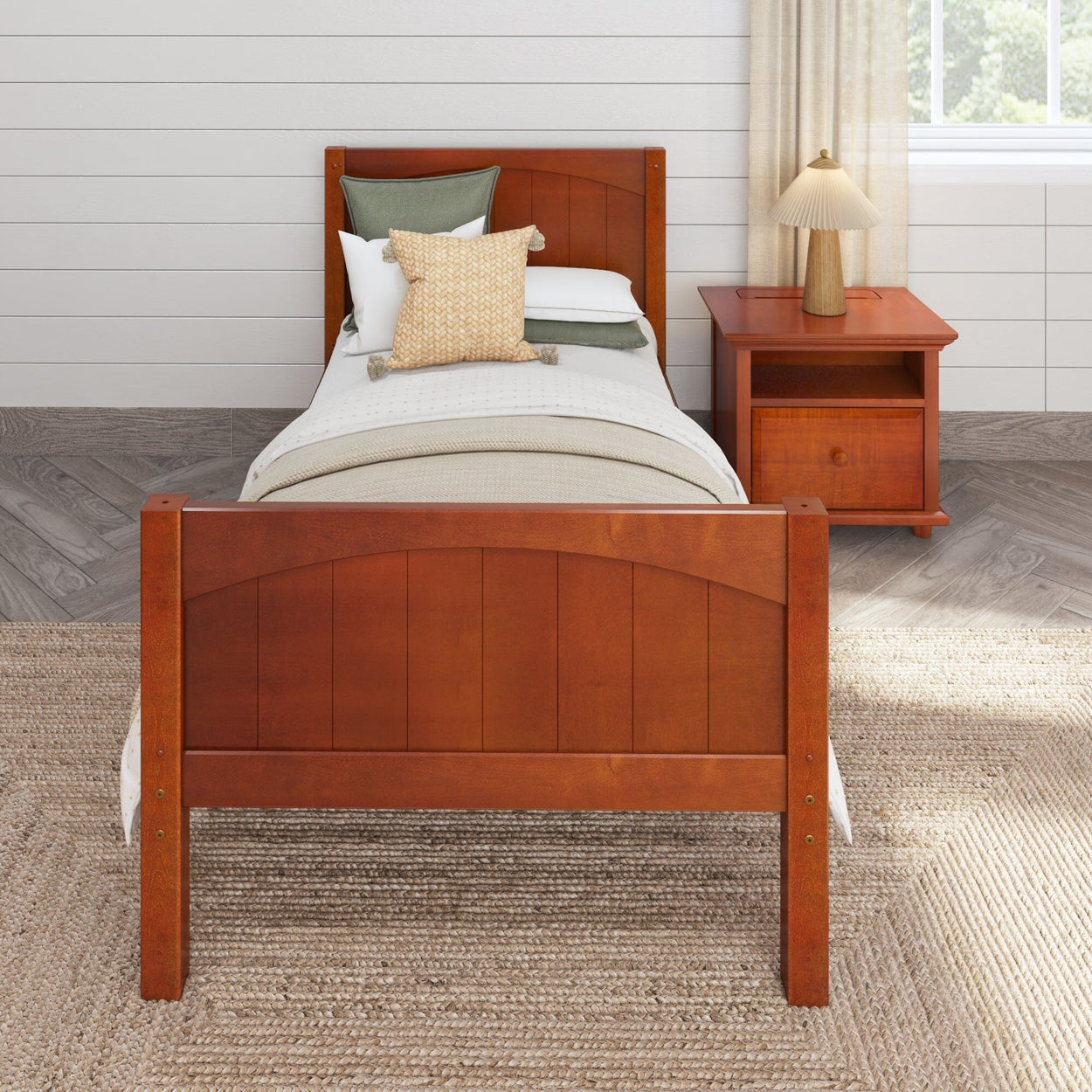 Wooden single bed with white bedding and green pillows next to a matching wooden nightstand in a cozy bedroom setting.