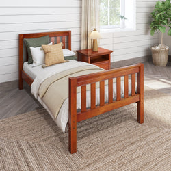 Wooden twin bed with cozy bedding and bedside table in a bright, rustic bedroom.