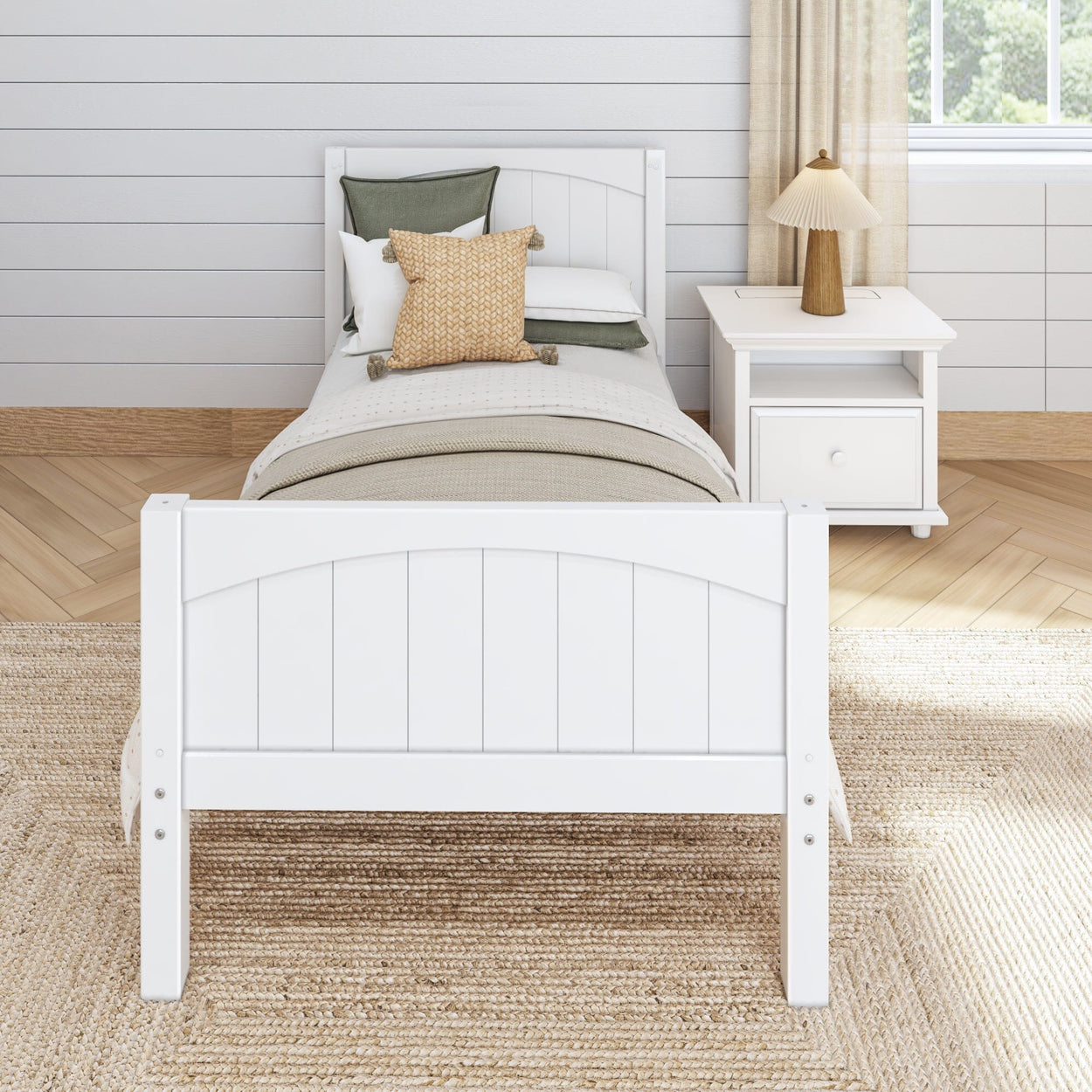 Single bed with white wooden frame and neutral bedding in a bright modern bedroom.
