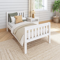 Cozy bedroom with a white wooden bed, neutral bedding, and a nightstand with a decorative lamp, enhancing a minimalist interior design.