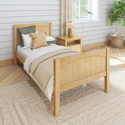 Single wooden bed with beige bedding and decorative pillows in a cozy, modern bedroom featuring a wooden nightstand and a potted plant.