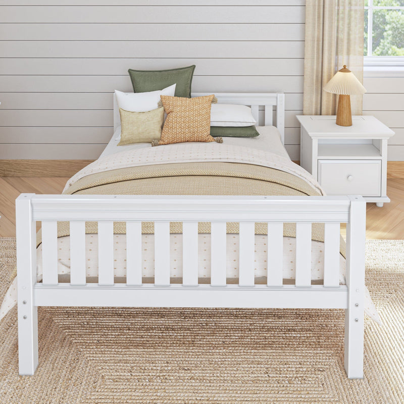 Cozy neutral bedroom with white wooden bed, beige bedding, textured green and tan throw pillows, shiplap wall, woven jute rug and bedside table with wooden lamp.
