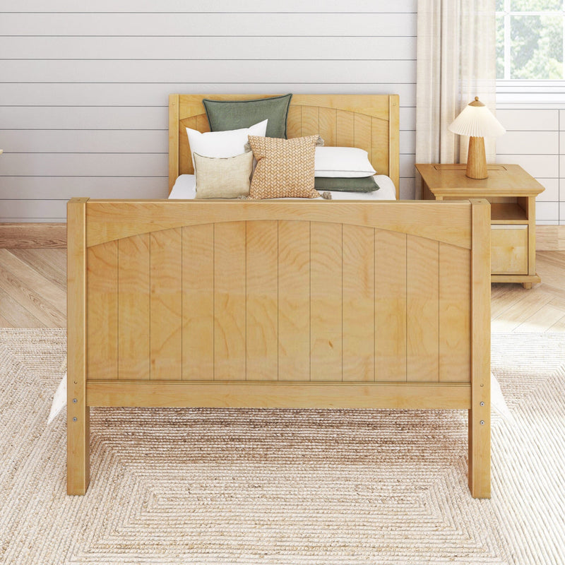 Scandinavian farmhouse bedroom with light wood bed frame, layered neutral and green pillows, woven jute rug, wooden nightstand and lamp against white shiplap wall and sunlit window