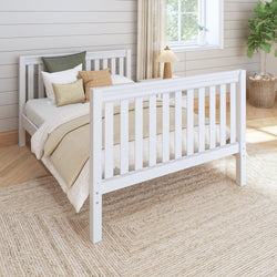 White wooden bed frame in cozy bedroom with natural light, soft cushions, and beige bedding.