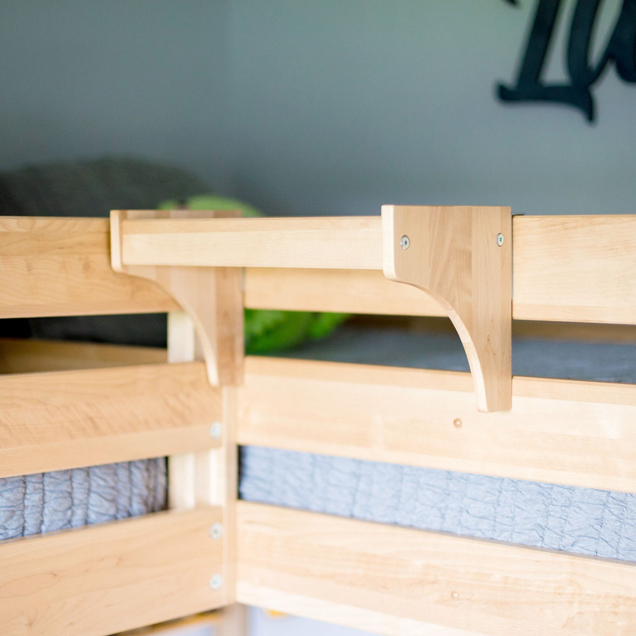 Wooden bunk bed corner detail with safety rail and soft mattress.