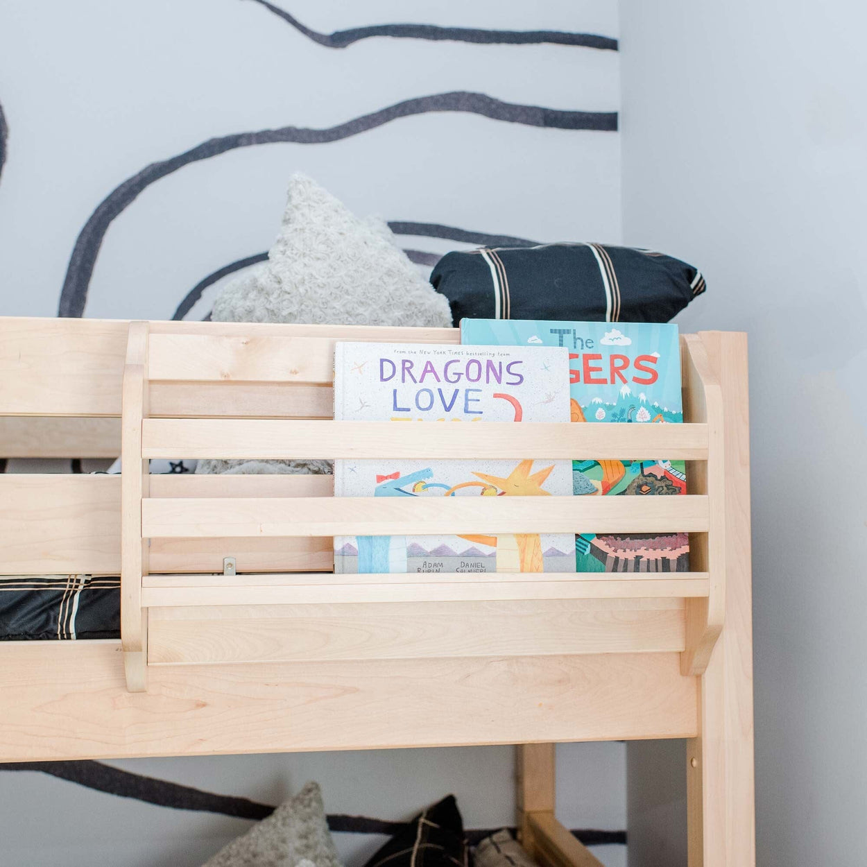 Children's wooden bunk bed with colorful children's books on the shelf, including "Dragons Love.