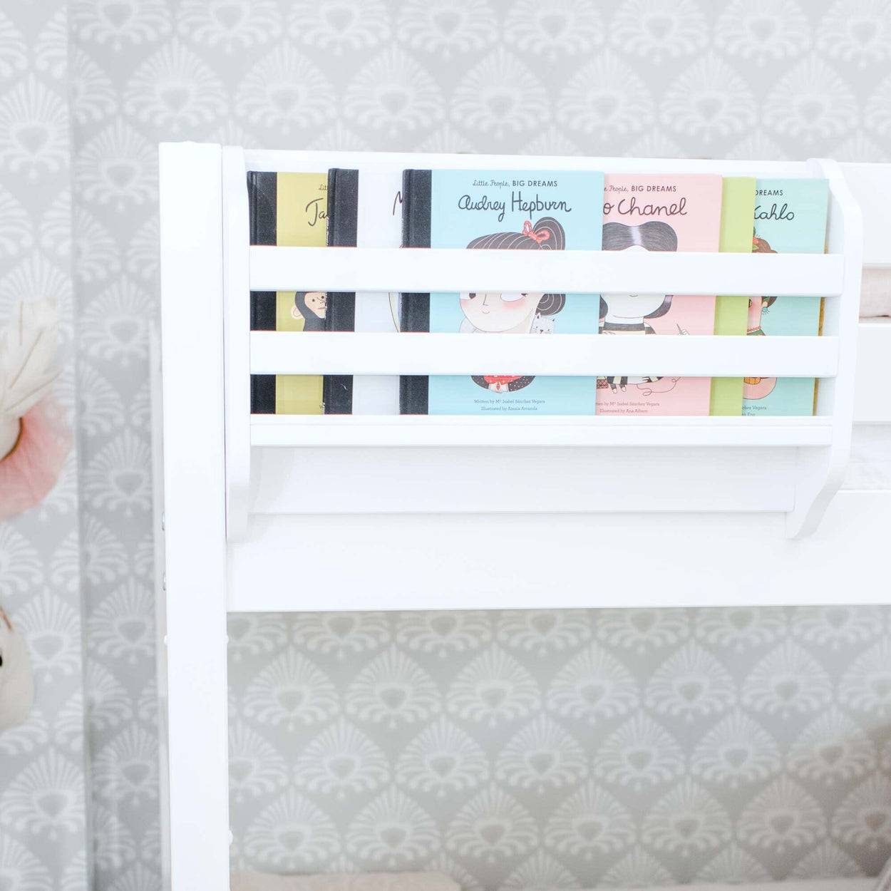 Children's books neatly arranged in a white wall-mounted bookshelf in a modern nursery room.