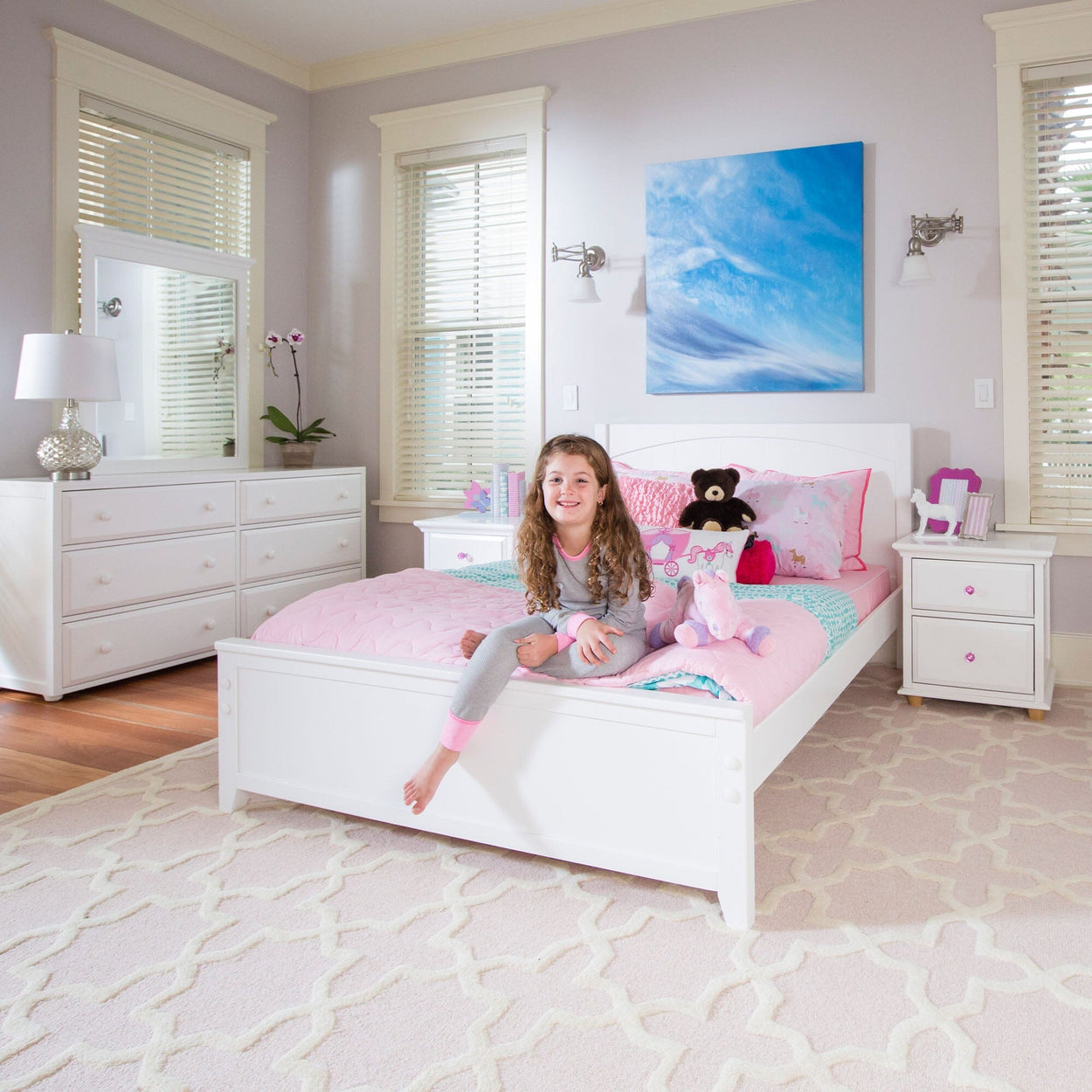 Bright and cozy girl's bedroom with white furniture, pink and blue bedding, and plush toys.