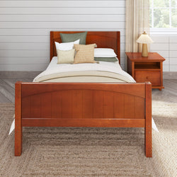 Wooden bed frame with white bedding and decorative pillows in a cozy bedroom setting with a bedside table and neutral decor.