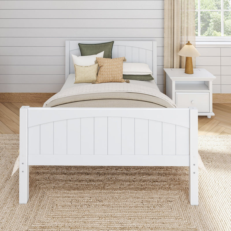 Cozy farmhouse bedroom with white wooden bed, neutral bedding and textured decorative pillows, shiplap wall and nightstand lamp by window