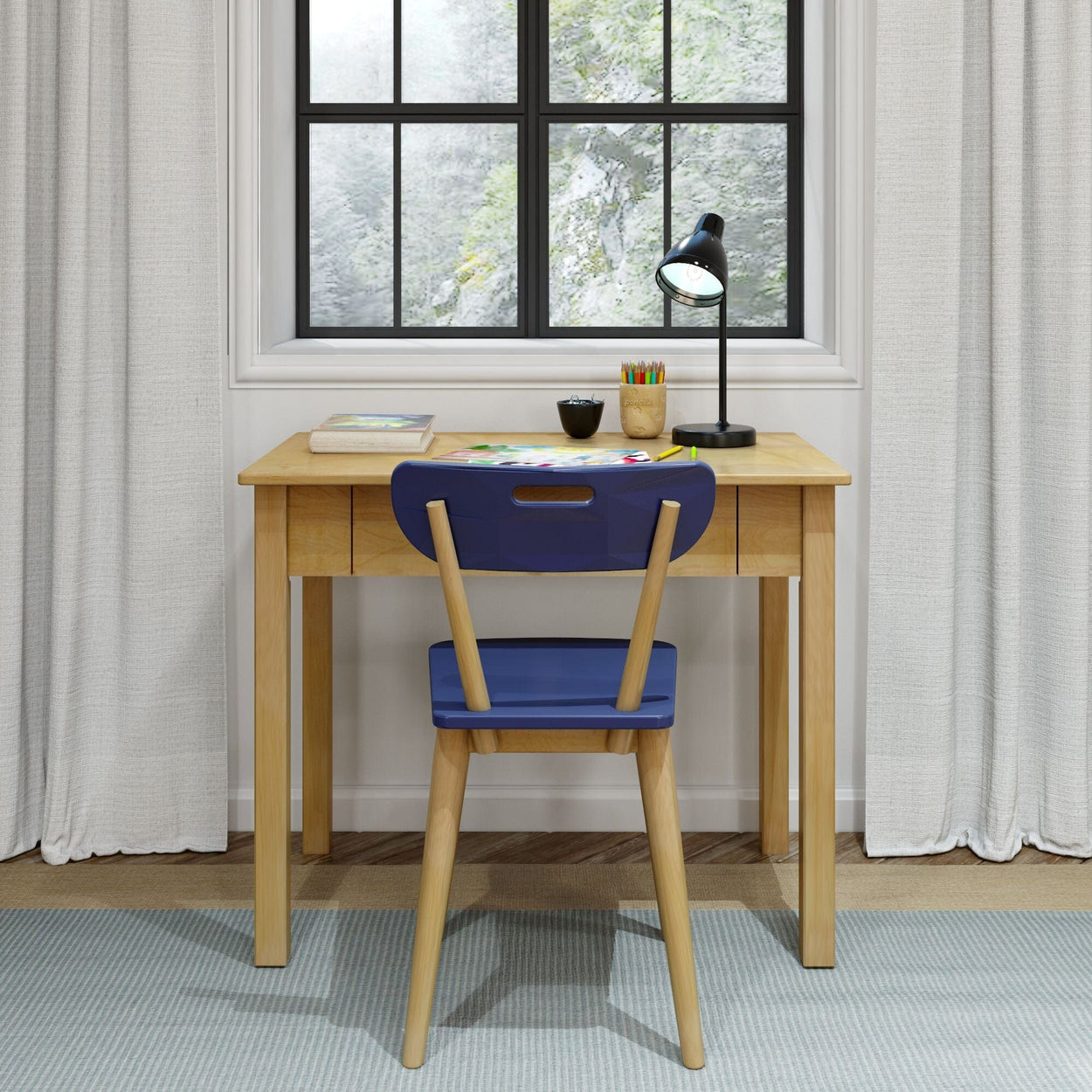Wooden desk setup by bright window with study supplies, blue chair, and lamp for an organized workspace.