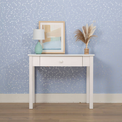 White console table with lamp, framed artwork, and decorative vase against a star-printed blue wall background.