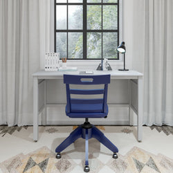 Office desk setup with a blue chair in a bright room, featuring a window view and modern decor.