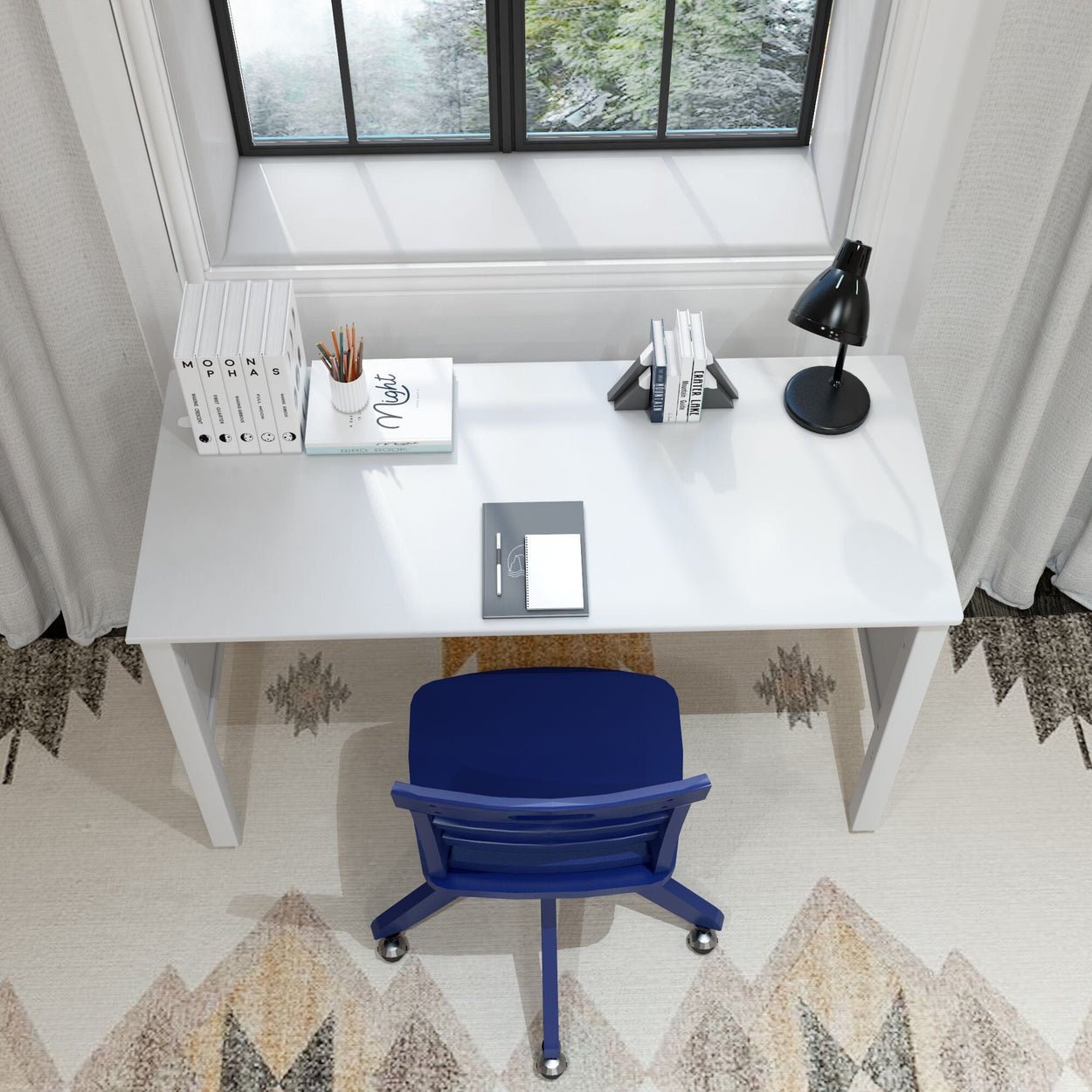 Modern home office setup with a white desk, blue chair, black lamp, books, and a scenic window view.