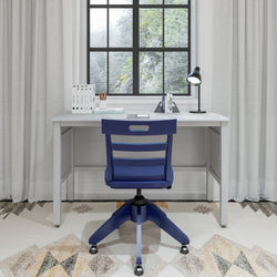 Stylish modern home office desk setup with a blue chair, window view, and desktop accessories.