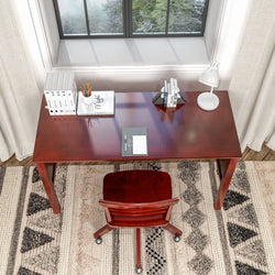 Modern home office setup with a wooden desk, chair, and window view, featuring a desk lamp, books, and stationery.