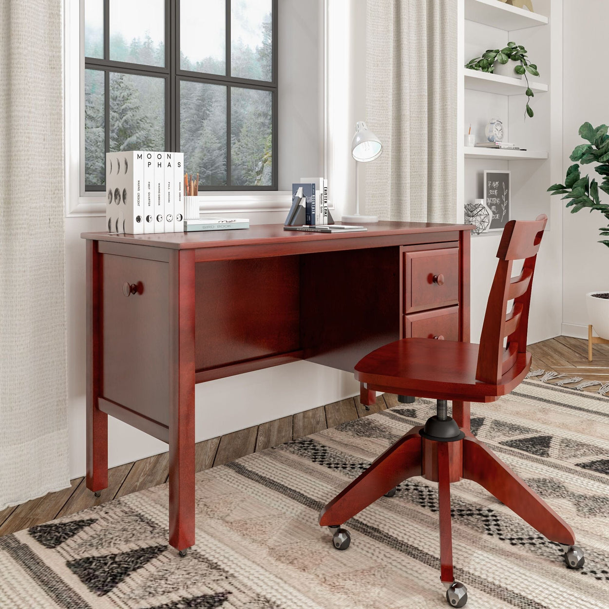 Red wooden desk and chair set in a modern home office with books, lamp, and large window background.