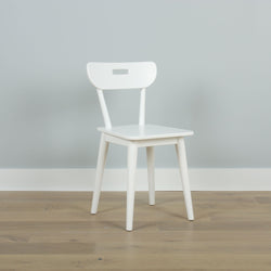 Modern white wooden chair on a light wood floor against a gray wall.