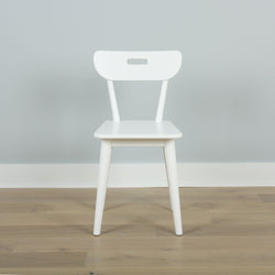 Modern white wooden chair on light wooden floor against gray wall background.