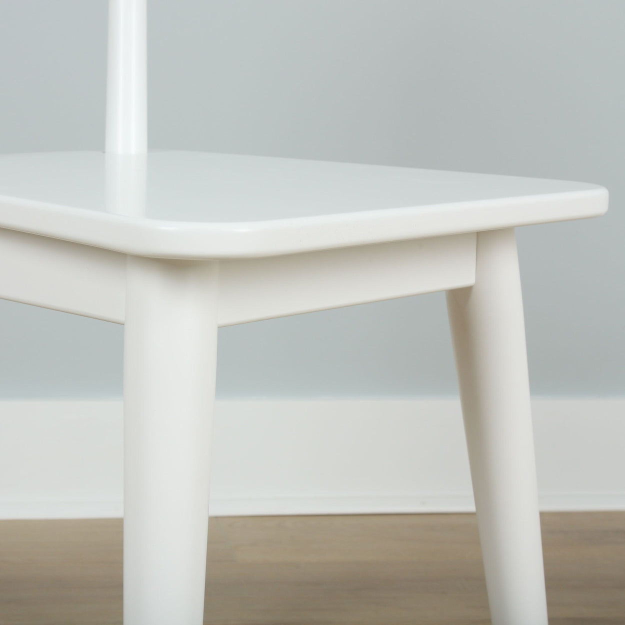 White modern chair with wooden legs in minimalist interior setting.
