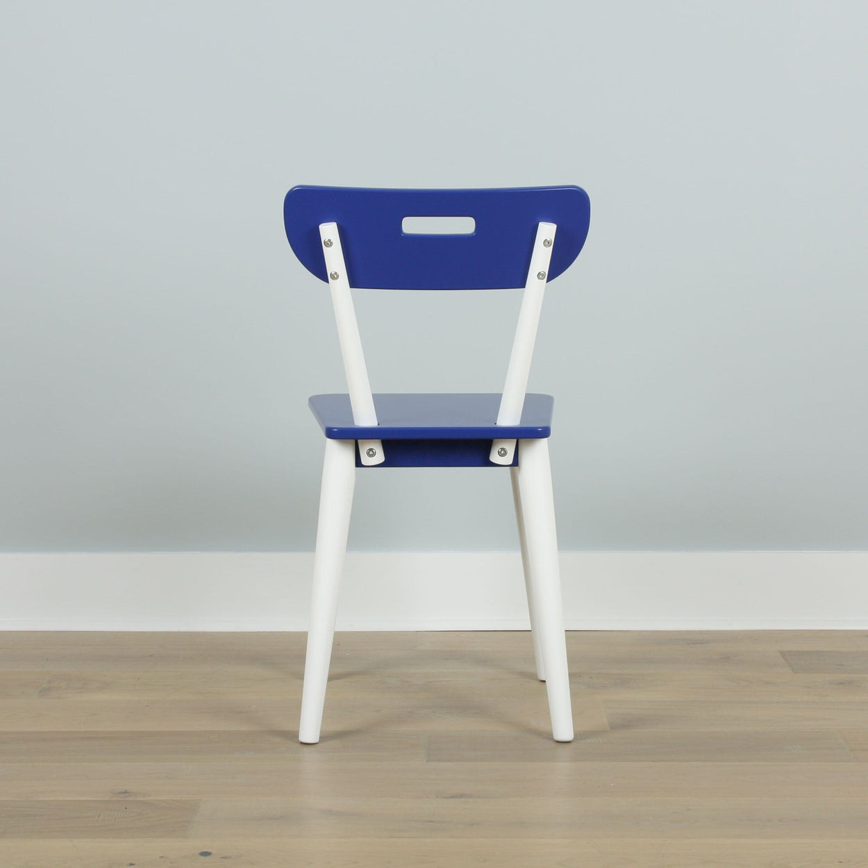 Blue and white modern chair on wooden floor against light gray wall, minimalist furniture design.
