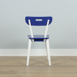 Blue and white modern chair on wooden floor against light gray wall, minimalist furniture design.