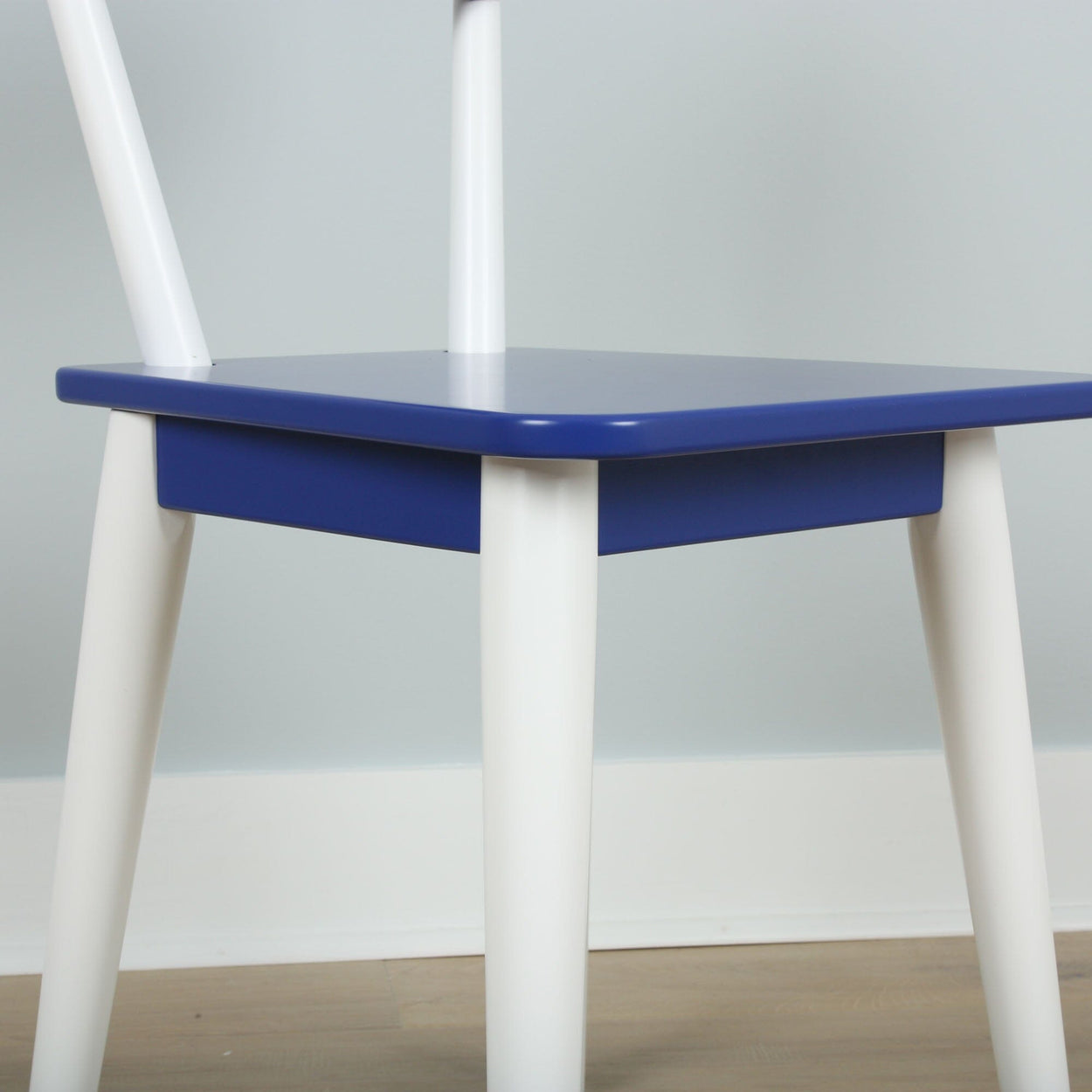 Colorful modern chair with blue seat and white legs in a minimalist design setting.