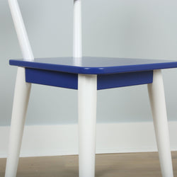 Colorful modern chair with blue seat and white legs in a minimalist design setting.