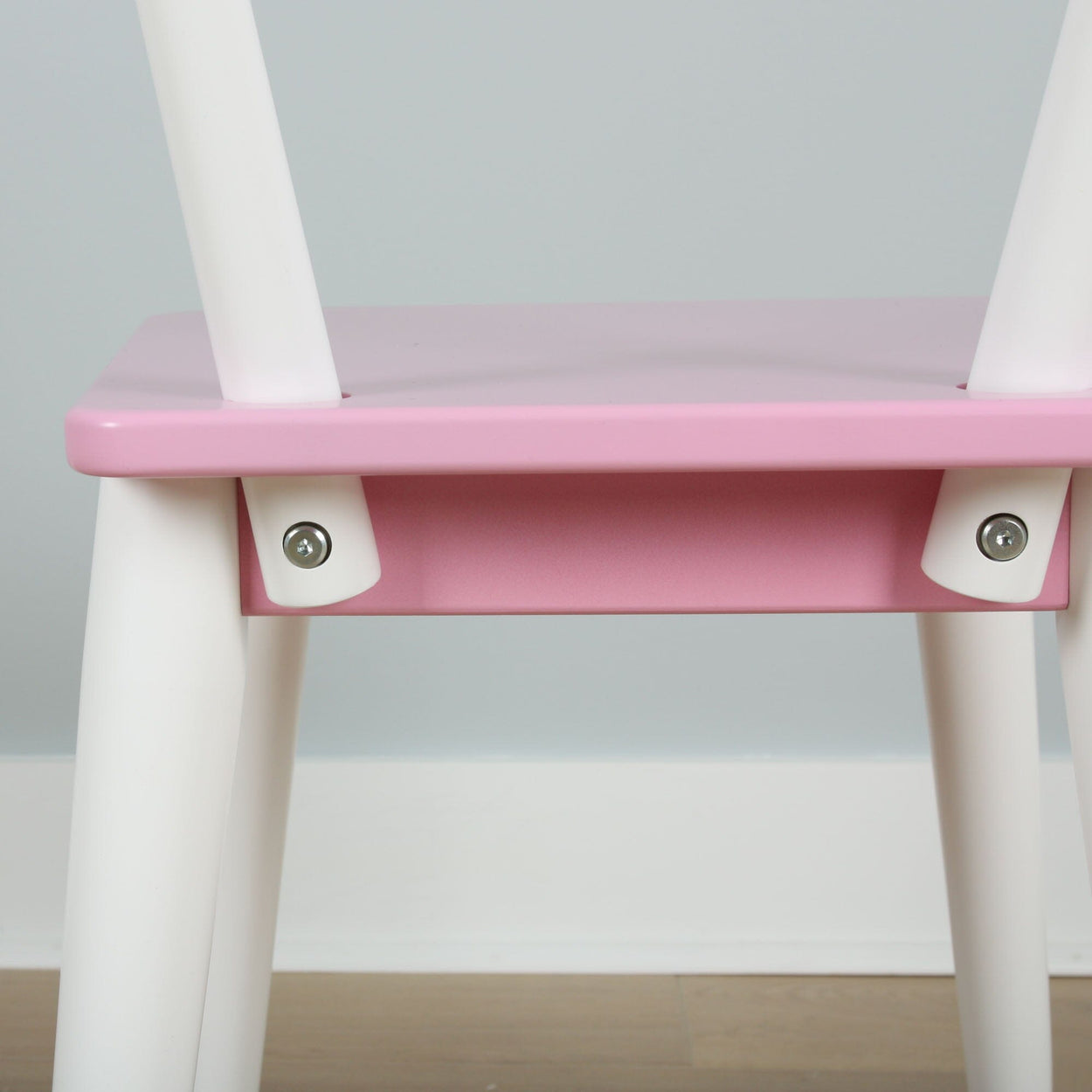 Pink and white children's chair with modern design and sturdy construction.