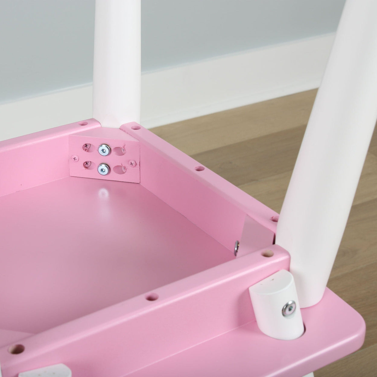 Pink wooden table with white legs on wooden floor.