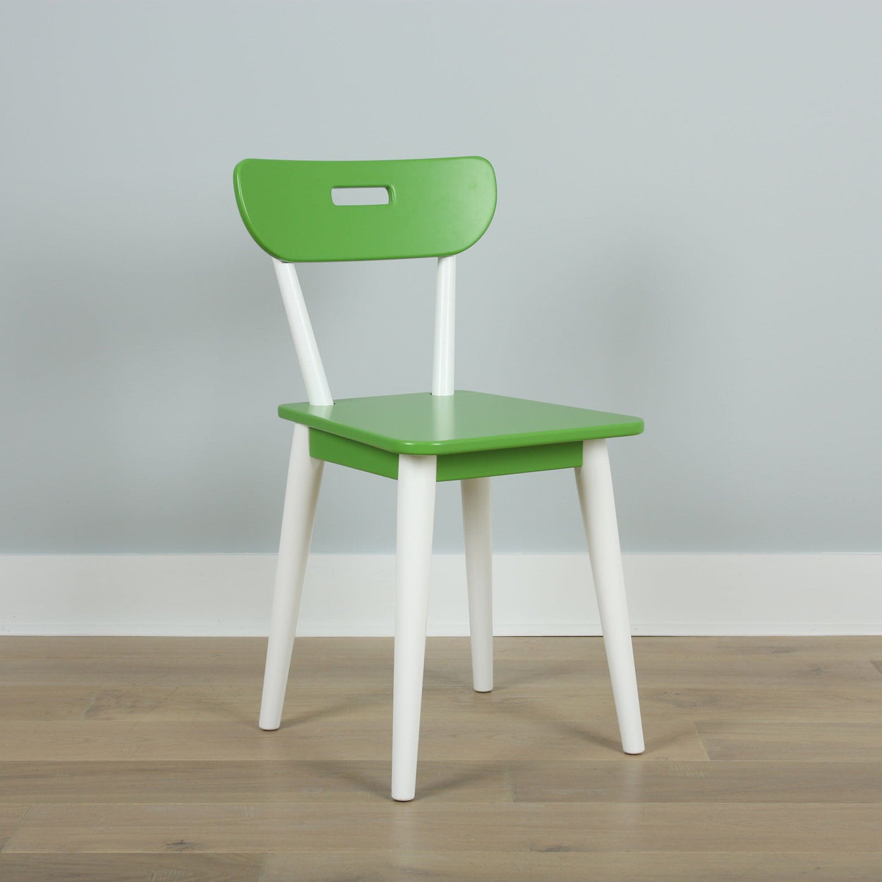 Green and white modern chair on wooden floor against a light gray wall.