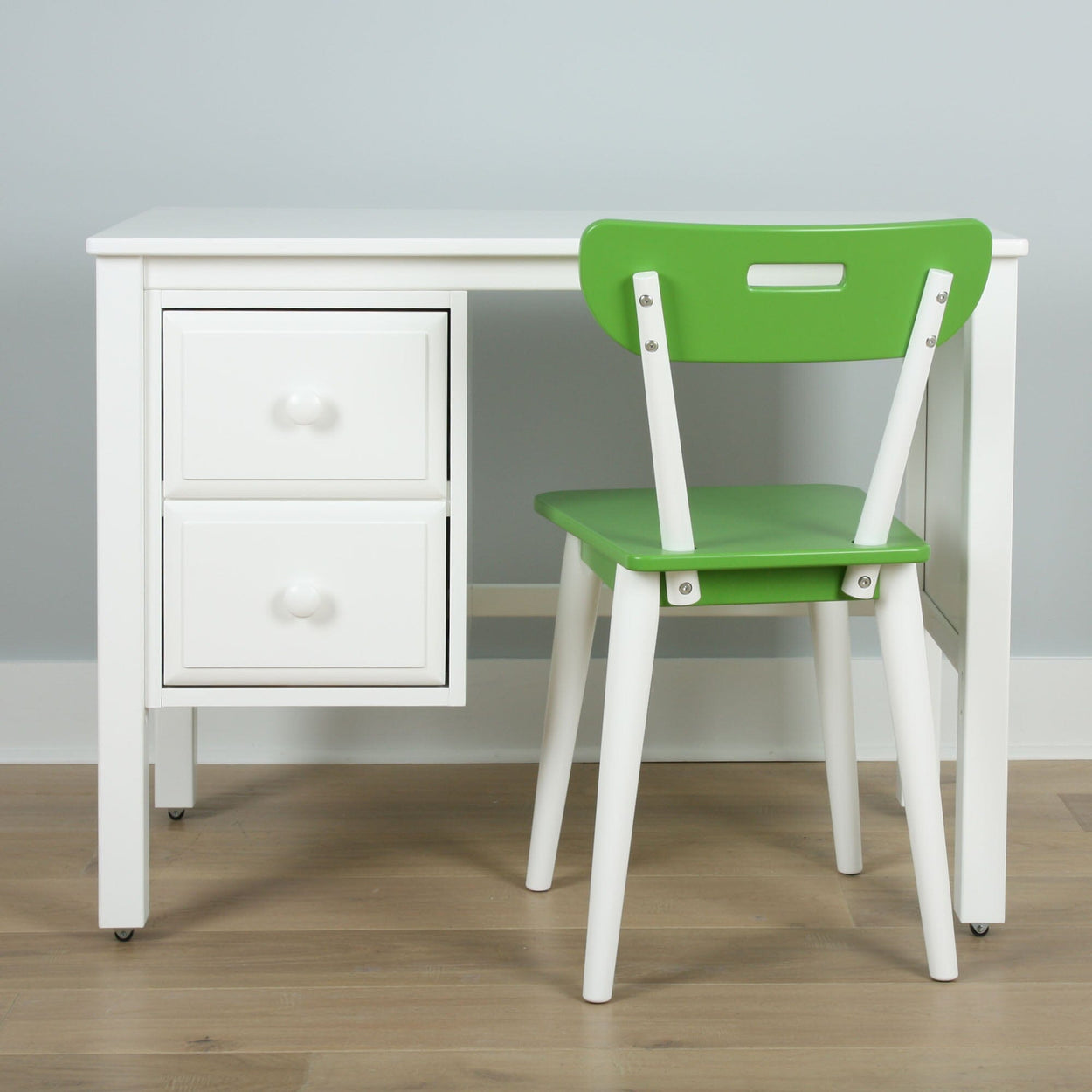 White desk with two drawers and a green chair on wooden floor, ideal for modern home office setups.