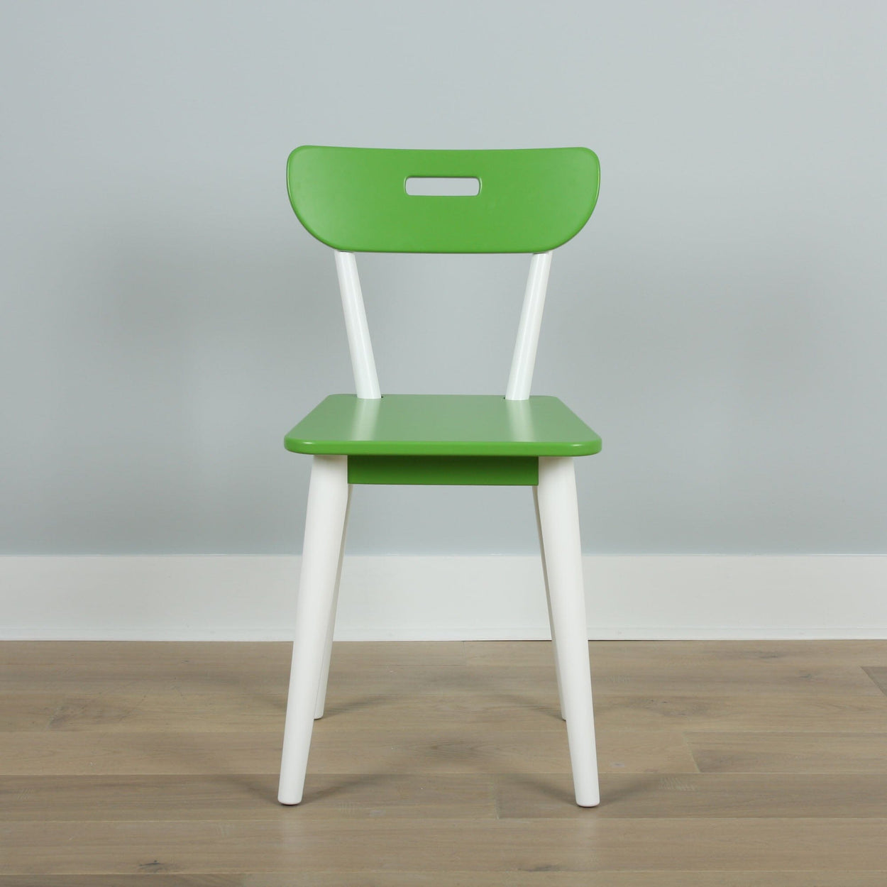 Green and white chair with modern design on a wooden floor against a gray wall.