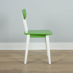 Green and white modern children's chair on wooden floor against gray wall.