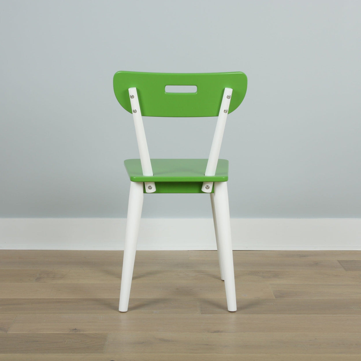 Green wooden chair with white legs on wooden floor, modern minimalist furniture design.